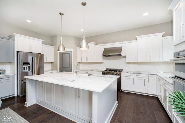 kitchen with under cabinet range hood, high quality appliances, tasteful backsplash, and dark wood finished floors