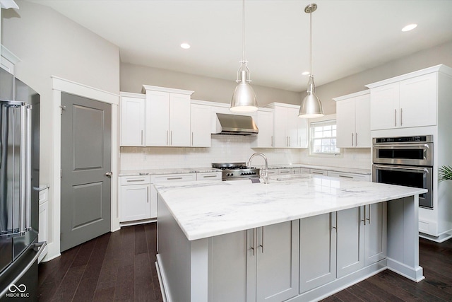 kitchen featuring high end appliances, dark wood-type flooring, tasteful backsplash, and wall chimney range hood