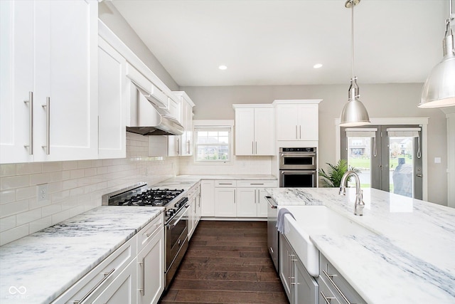 kitchen featuring stainless steel appliances, a sink, white cabinetry, exhaust hood, and dark wood-type flooring