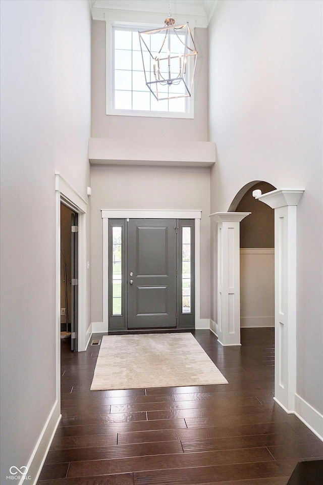 foyer featuring hardwood / wood-style flooring, arched walkways, and a high ceiling