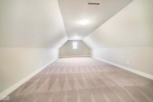 additional living space with carpet, visible vents, lofted ceiling, and baseboards