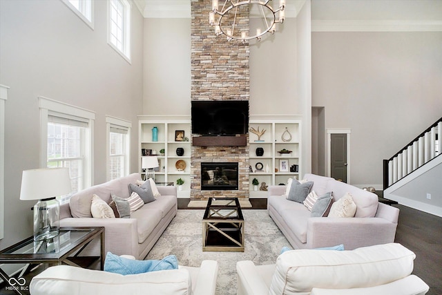 living area with wood finished floors, a stone fireplace, a chandelier, and a towering ceiling
