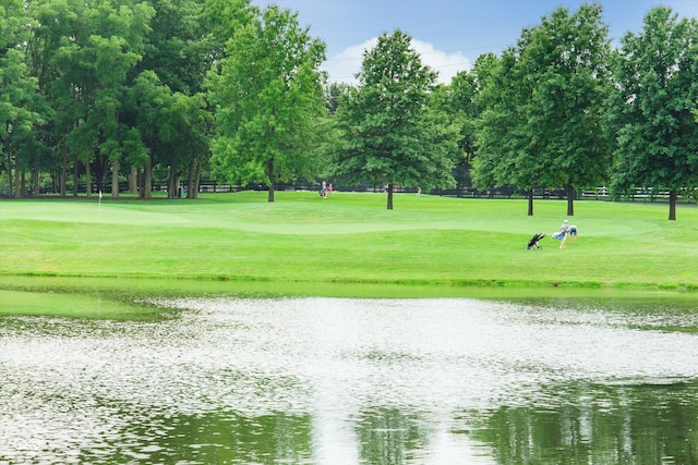 view of home's community with golf course view, a lawn, and a water view