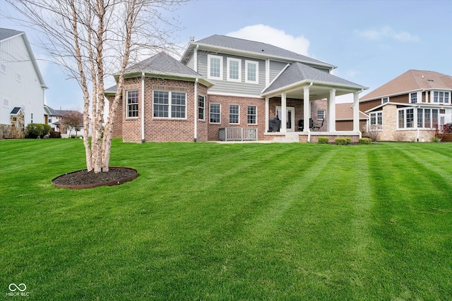 back of property with a lawn and brick siding