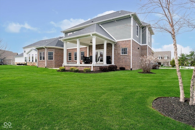 rear view of property with a lawn, brick siding, a patio area, and ceiling fan