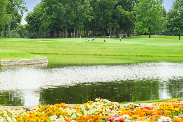 view of home's community with a lawn, a water view, and view of golf course