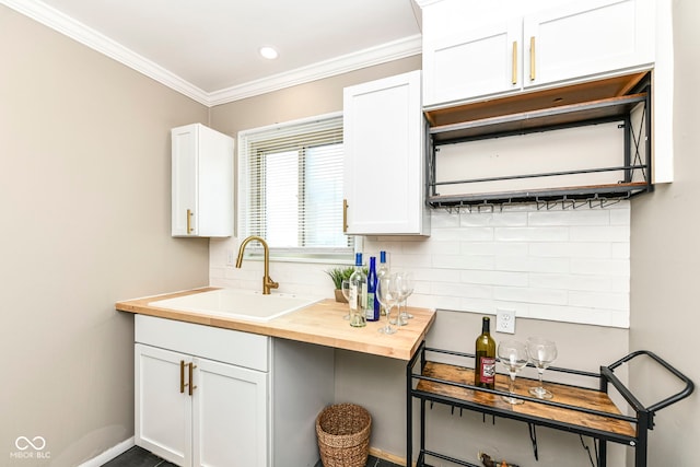 kitchen featuring a sink, ornamental molding, butcher block counters, white cabinetry, and backsplash