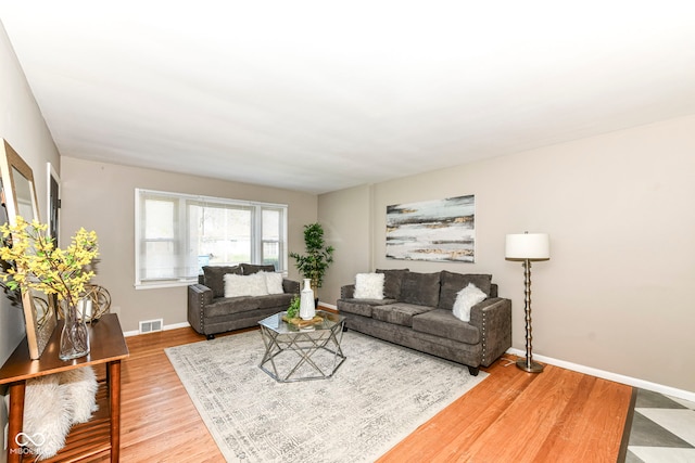 living room with visible vents, baseboards, and wood finished floors