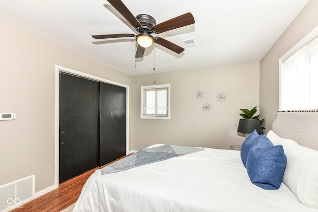 bedroom featuring visible vents, a closet, a ceiling fan, and wood finished floors