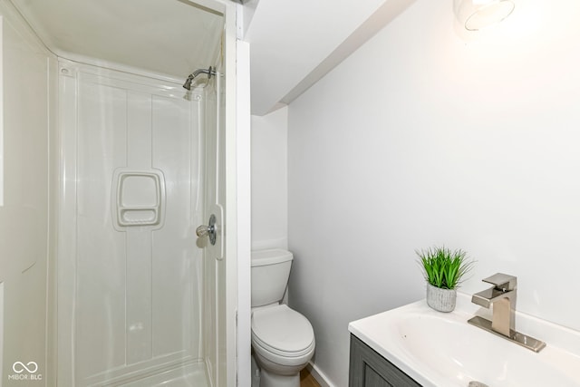 bathroom featuring toilet, vanity, baseboards, and a shower
