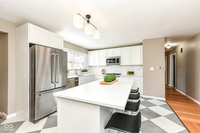 kitchen featuring appliances with stainless steel finishes, light countertops, white cabinetry, and a breakfast bar