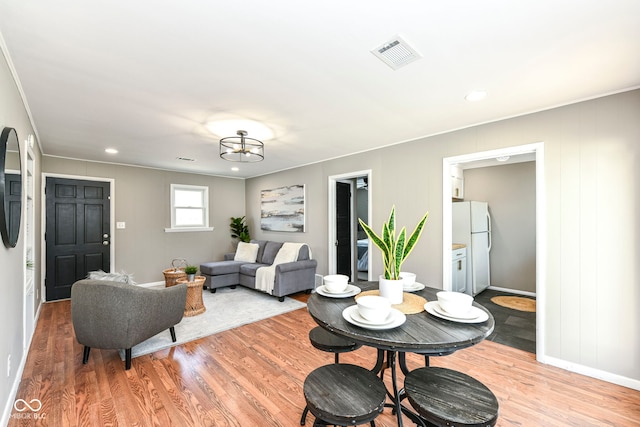 living room with light wood-style floors, crown molding, visible vents, recessed lighting, and baseboards