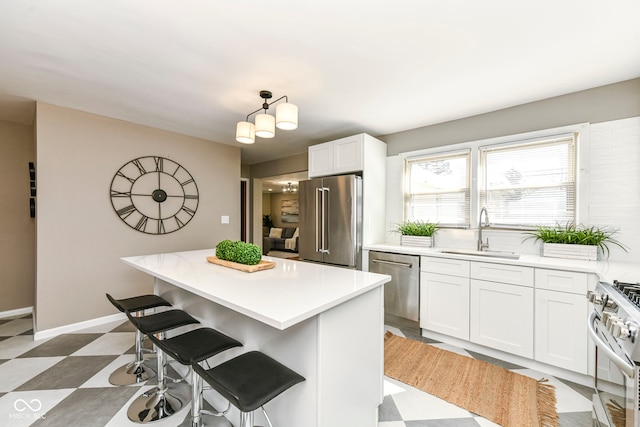 kitchen with a sink, light countertops, a kitchen breakfast bar, white cabinetry, and stainless steel appliances