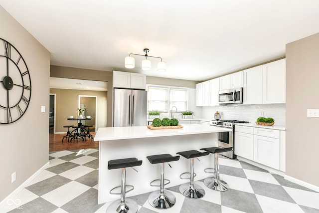 kitchen with stainless steel appliances, white cabinetry, a breakfast bar area, and light floors