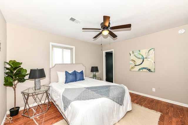 bedroom featuring wood finished floors, baseboards, a ceiling fan, and visible vents