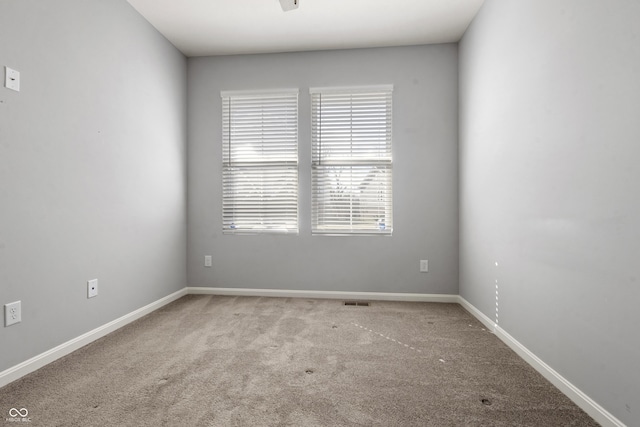 spare room featuring baseboards, visible vents, and carpet floors