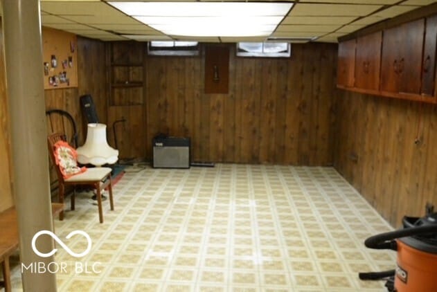 finished below grade area featuring wood walls, light floors, and a drop ceiling