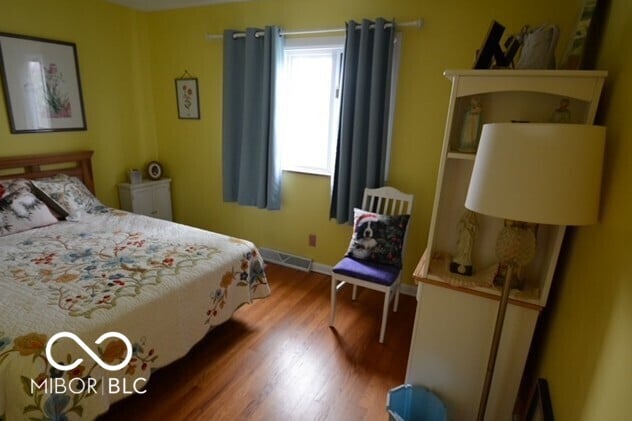 bedroom with wood finished floors, visible vents, and baseboards