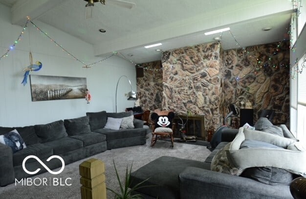 living room with a fireplace, carpet, a ceiling fan, and beamed ceiling