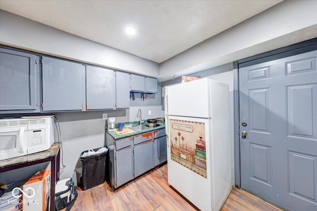 215 S Warman Ave, Indianapolis, IN 46222 - kitchen with white appliances, a textured ceiling, a sink, and light wood finished floors