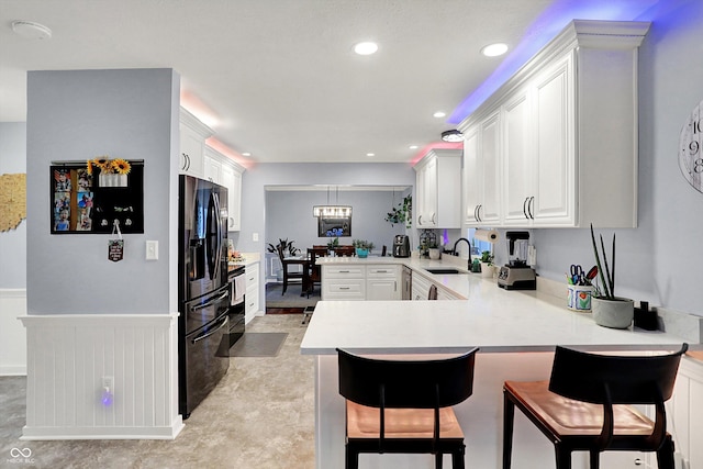 6820 W Forest Brook Dr, Fountaintown, IN 46130 - kitchen featuring a sink, a peninsula, black fridge, light countertops, and a kitchen breakfast bar