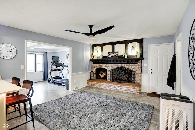 6820 W Forest Brook Dr, Fountaintown, IN 46130 - living room featuring a wainscoted wall, ceiling fan, a fireplace, and heating unit