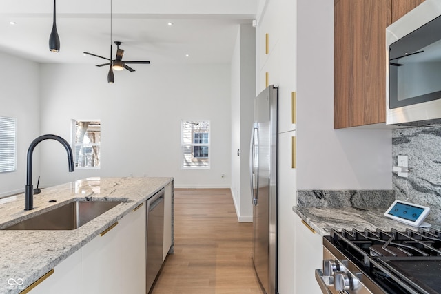 2362 English Ave, Indianapolis, IN 46201 - kitchen featuring a sink, appliances with stainless steel finishes, modern cabinets, light wood-style floors, and decorative backsplash