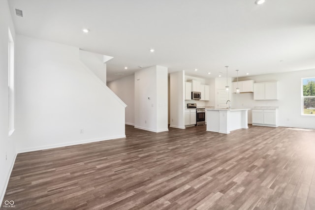 unfurnished living room with wood finished floors, recessed lighting, a sink, and visible vents