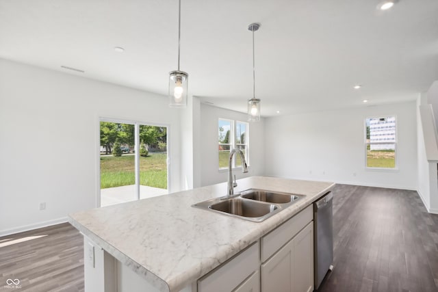 kitchen with light countertops, a center island with sink, a sink, open floor plan, and stainless steel dishwasher