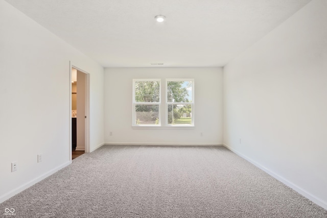 spare room with light carpet and baseboards