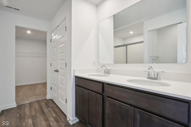 bathroom featuring a shower stall, double vanity, visible vents, and a sink