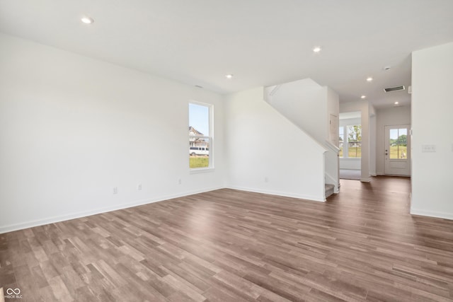 spare room featuring visible vents, baseboards, stairs, wood finished floors, and recessed lighting