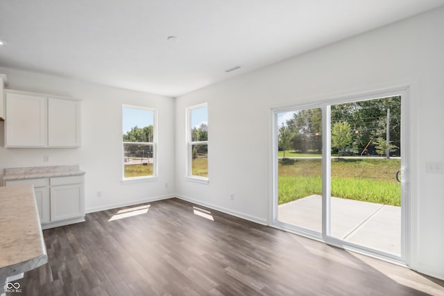 unfurnished dining area featuring dark wood-style flooring, baseboards, and visible vents