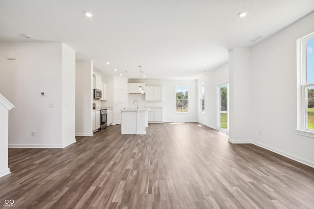 unfurnished living room with baseboards, a sink, recessed lighting, and dark wood-style flooring