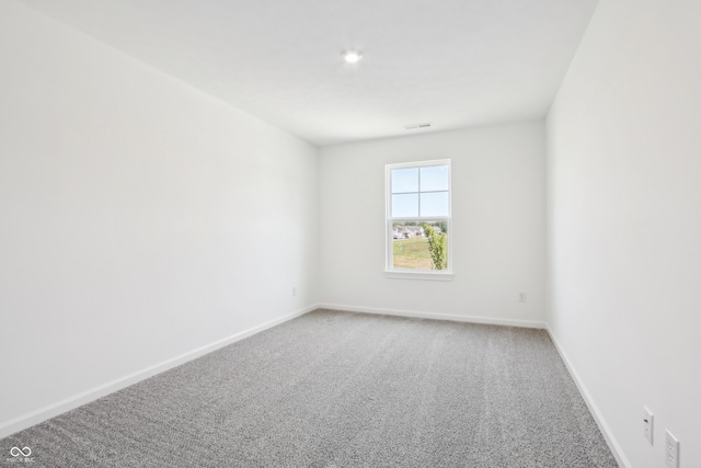 carpeted empty room featuring baseboards and visible vents