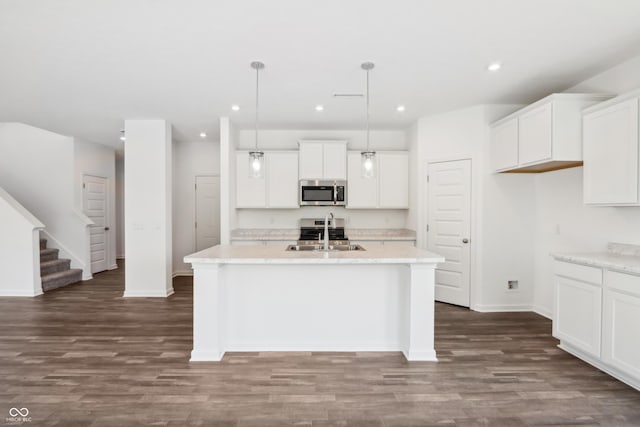 kitchen featuring a center island with sink, dark wood-style floors, a sink, and stainless steel microwave