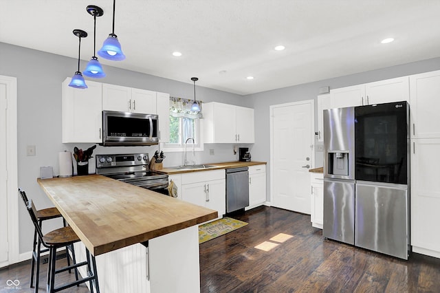 8315 San Marcos Cir, Indianapolis, IN 46256 - kitchen featuring appliances with stainless steel finishes, butcher block counters, dark wood finished floors, pendant lighting, and white cabinets