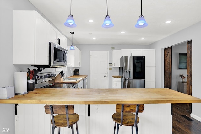 8315 San Marcos Cir, Indianapolis, IN 46256 - kitchen with appliances with stainless steel finishes, butcher block counters, a peninsula, hanging light fixtures, and recessed lighting