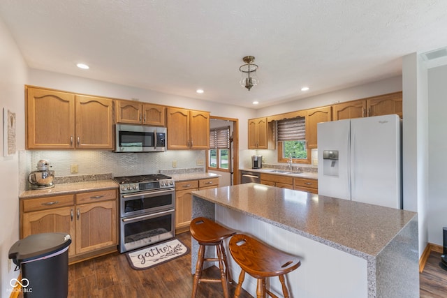 1864 Holiday Pines Dr, Brownsburg, IN 46112 - kitchen featuring appliances with stainless steel finishes, a sink, dark wood-style flooring, a kitchen island, and recessed lighting