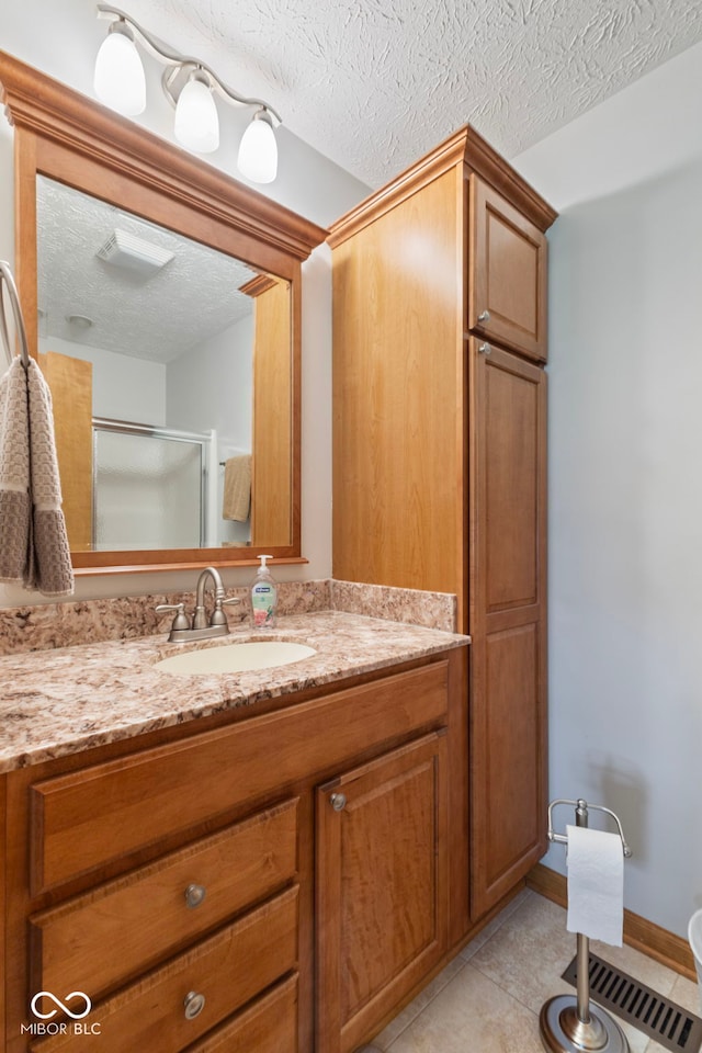 1864 Holiday Pines Dr, Brownsburg, IN 46112 - full bathroom featuring vanity, tile patterned floors, a shower with shower door, a textured ceiling, and baseboards