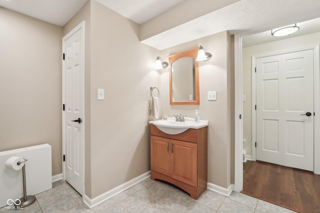 bathroom with tile patterned flooring, baseboards, and vanity