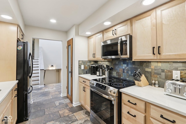 kitchen with tasteful backsplash, light brown cabinets, stone finish flooring, and stainless steel appliances
