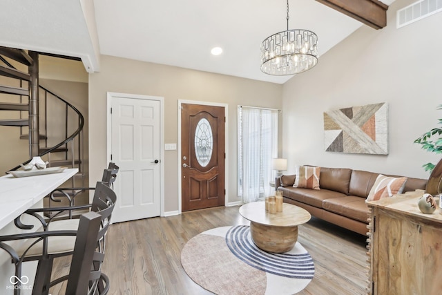 entrance foyer featuring a notable chandelier, baseboards, stairway, visible vents, and wood finished floors