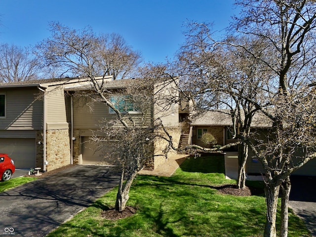 view of front facade with a garage, aphalt driveway, stone siding, and a front lawn