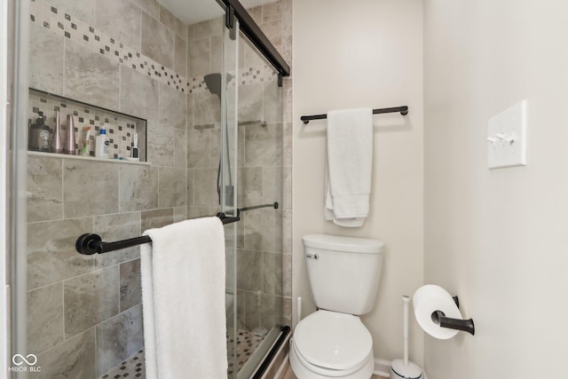 bathroom with a shower stall, baseboards, and toilet