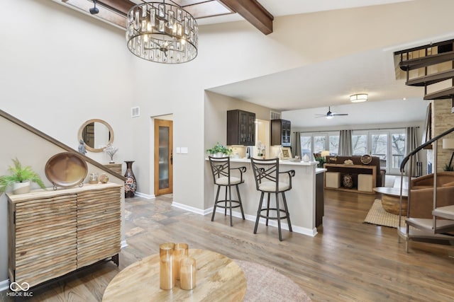 interior space featuring ceiling fan with notable chandelier, a kitchen bar, a peninsula, light countertops, and baseboards