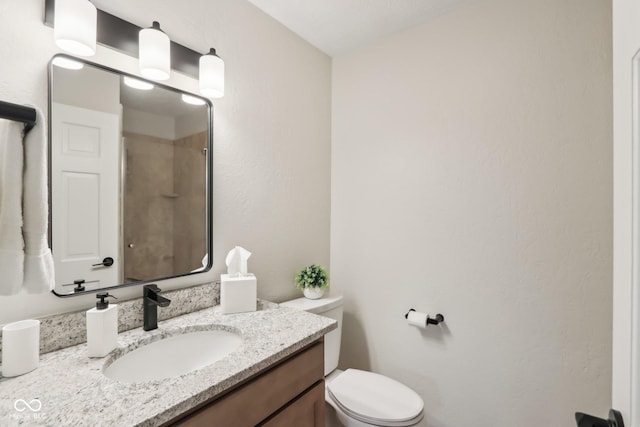 bathroom featuring toilet, a shower, and vanity