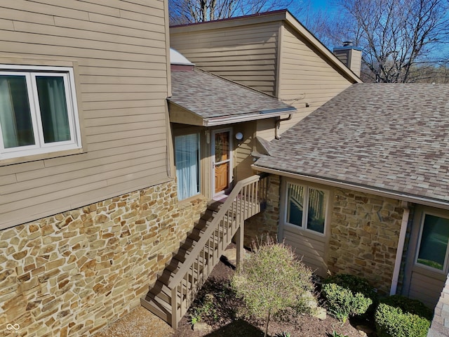 view of home's exterior with stone siding and roof with shingles