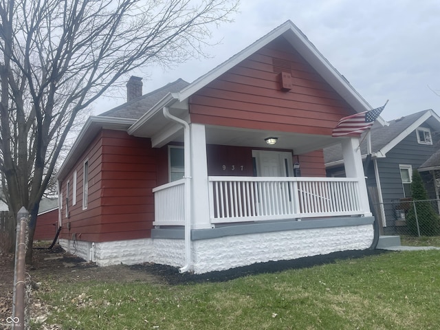 bungalow-style house with a chimney, a shingled roof, and covered porch