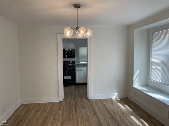 unfurnished dining area with baseboards, wood finished floors, ornamental molding, and an inviting chandelier